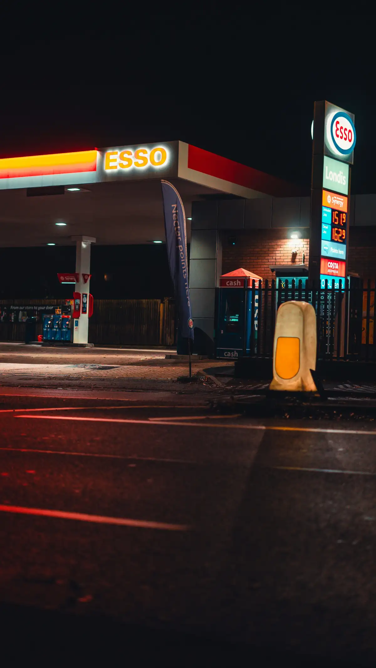 a gas station at night with a lit up sign